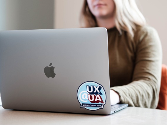 Girl on her laptop with a UX@UA sticker