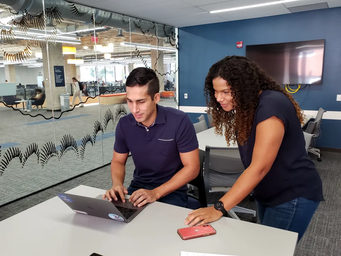 A staff member and a student worker looking at a laptop together