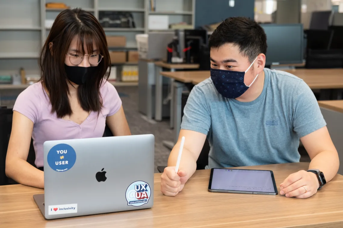 A staff member consulting with a student who's using a laptop